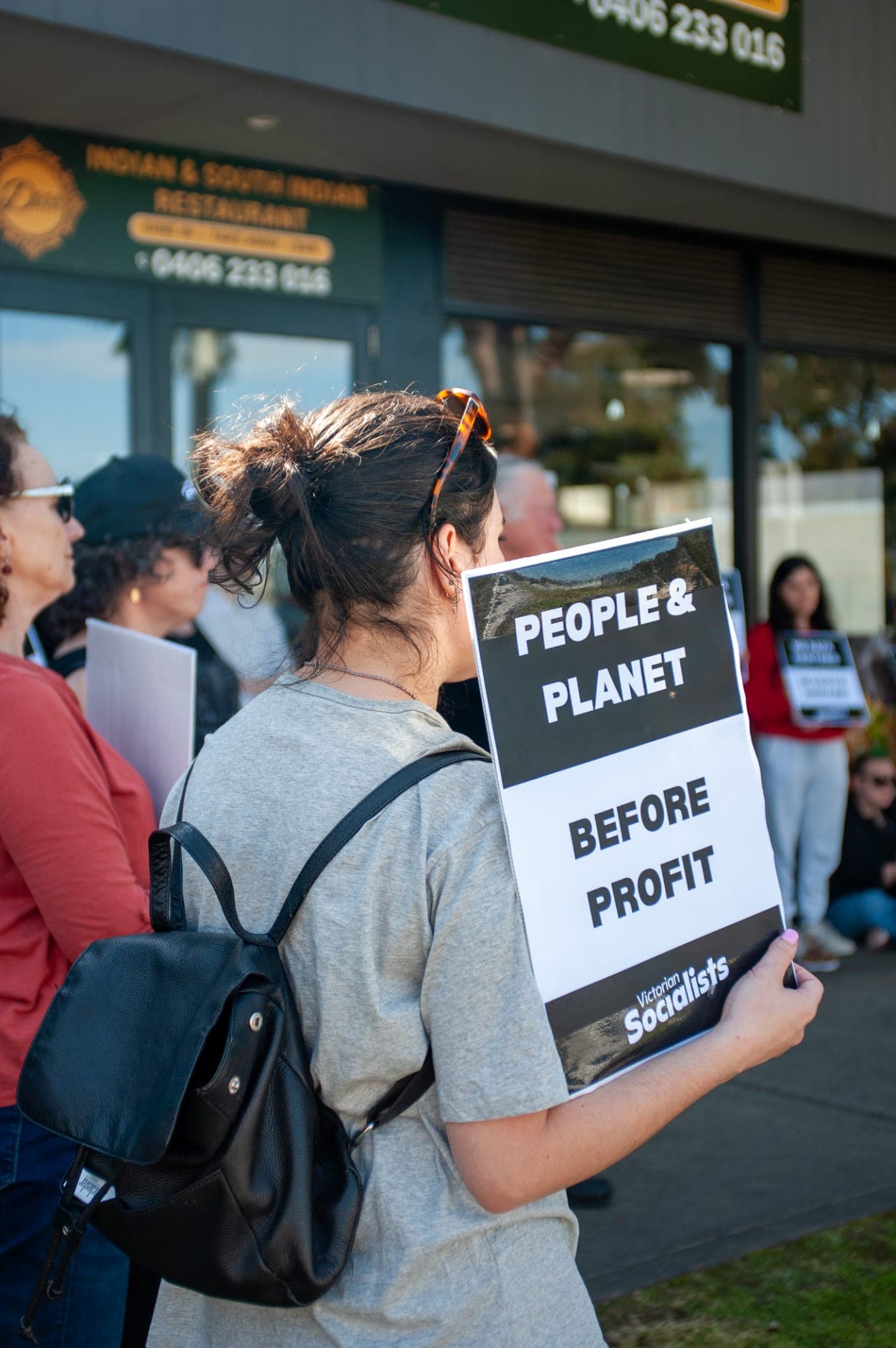 A woman holds a placard that reads 'people and planet before profit'